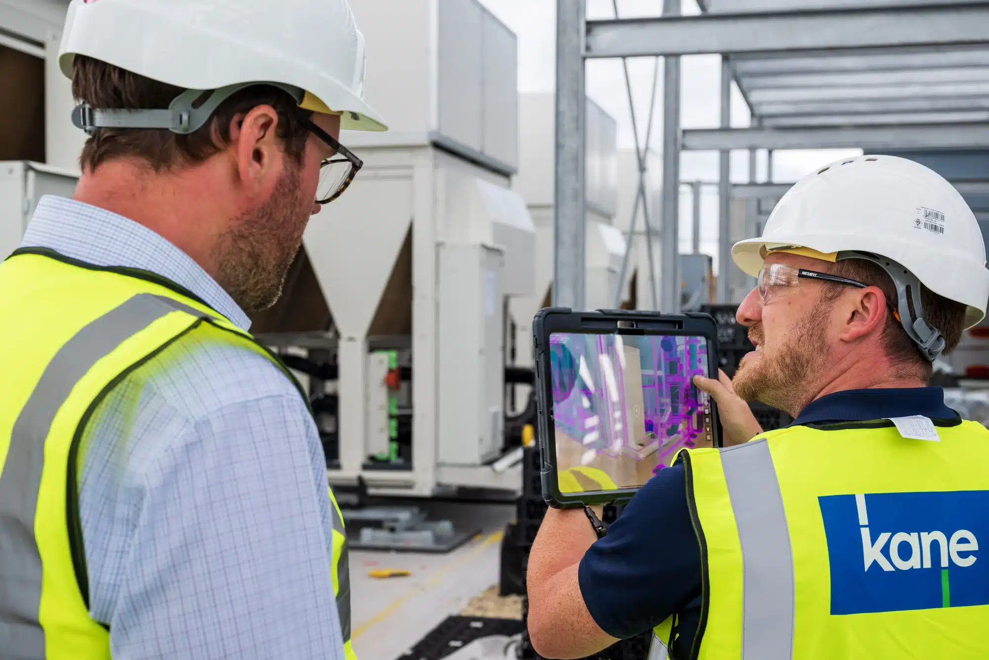 Site team reviewing an AR model overlay on a tablet beside rooftop HVAC units
