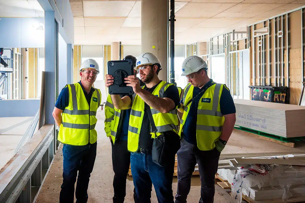 Construction team walking the site while reviewing issues on a tablet